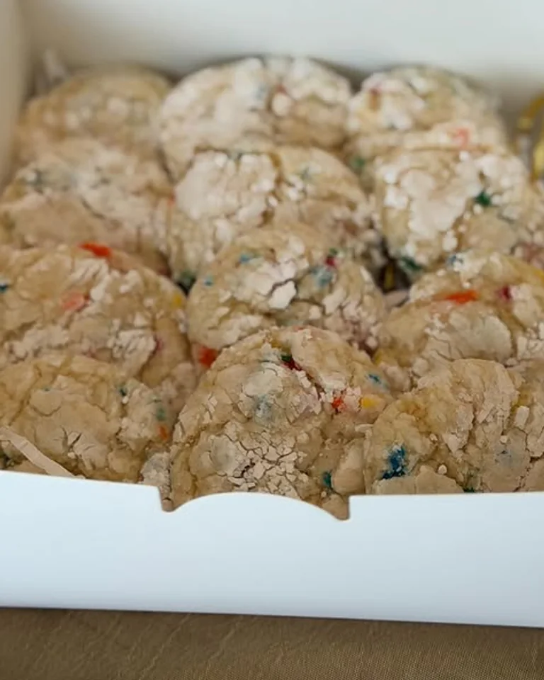 A box of pale Funfetti cookies with colorful sprinkle inclusions, photographed by The Cookie Cartel NJ.
