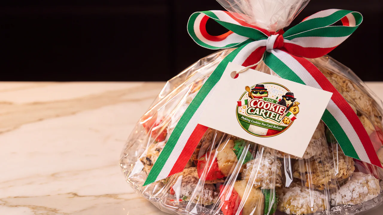 A cellophane-wrapped Cookie Cartel cookie assortment tied with a red, white and green ribbon and the Cartel seal.